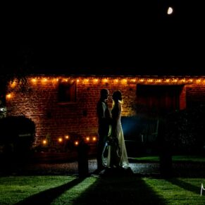 Dramatic wedding photography at night-time of the newlyweds silhouetted against their Buckinghamshire barn venue