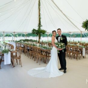 Buckinghamshire photography of a summer festival style rustic wedding marquee interior with the newlyweds in the foreground 