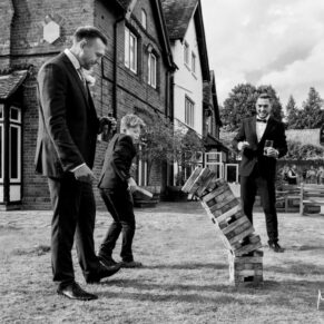Photography of the ushers playing Jenga in the gardens at this Buckinghamshire pub wedding 