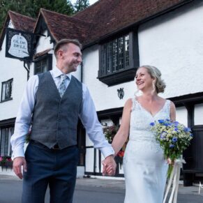 Photography of the newlyweds taking a stroll at their Buckinghamshire pub wedding in front of the historic building