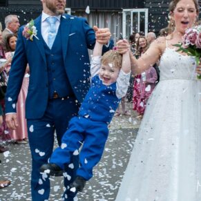 Photography of giggling pageboy being swung though the air in the confetti aisle at this Buckinghamshire pub wedding