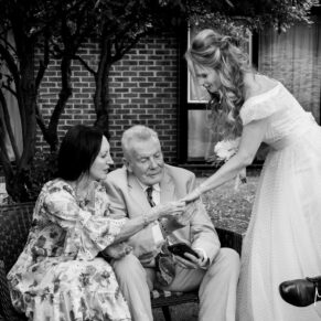 Photography of the bride and her parents enjoying a chat in the gardens at Fredrick's Hotel in Maidenhead on her wedding day