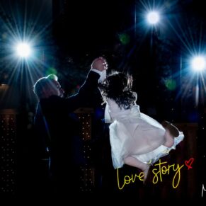 Winters Tale Country Barn wedding photography of the groom and the best man hoisting the young flower girl into the air on the dance-floor with starry lights behind